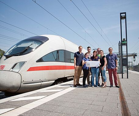 Studierende mit Professor am Bahnhof